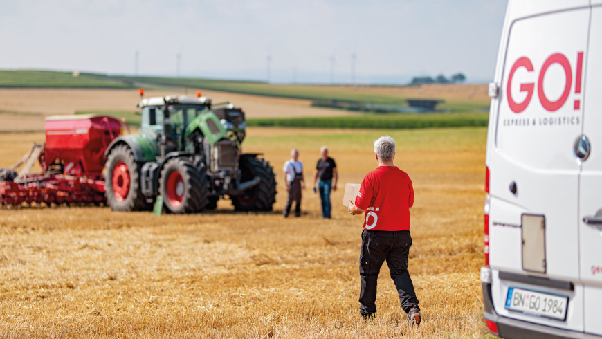 Lieferfahrzeug beim Traktor auf dem Feld